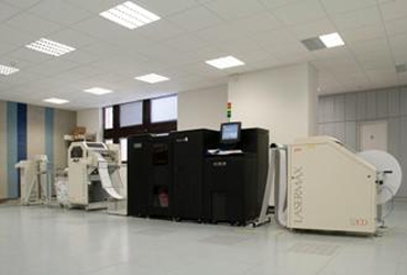 Coworkers walk by an HP Laserjet MFP 630 printer in an office.